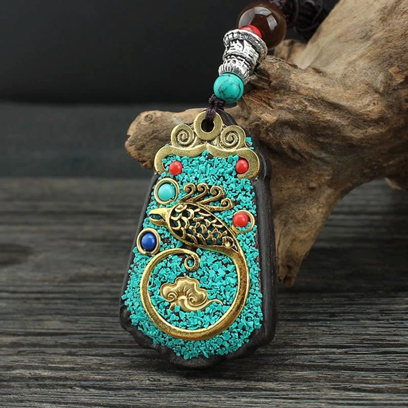 Golden Phoenix variant of Tibetan wealth thangka pendant showing phoenix rebirth symbolism with ornate gold filigree and detailed enamel work
