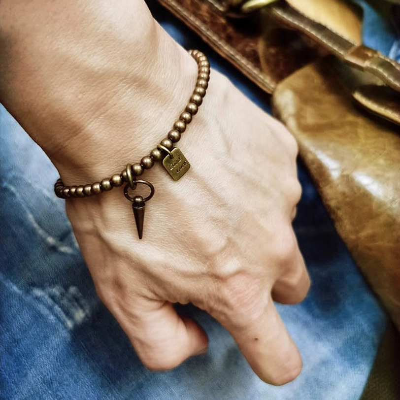 Copper prosperity bracelet worn on male wrist with casual denim and leather backdrop showing everyday wear