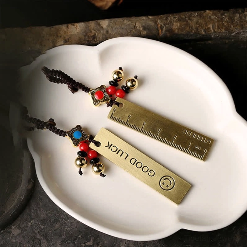 Good Luck brass tag keychains pair with engraved text and smiley pattern on white plate with size ruler reference