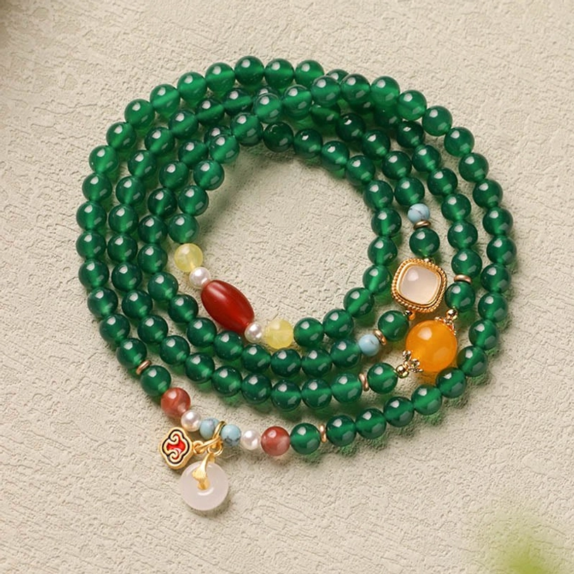 Three-quarter view of green agate Tibetan mala showing all decorative peace buckle charms and gemstone details