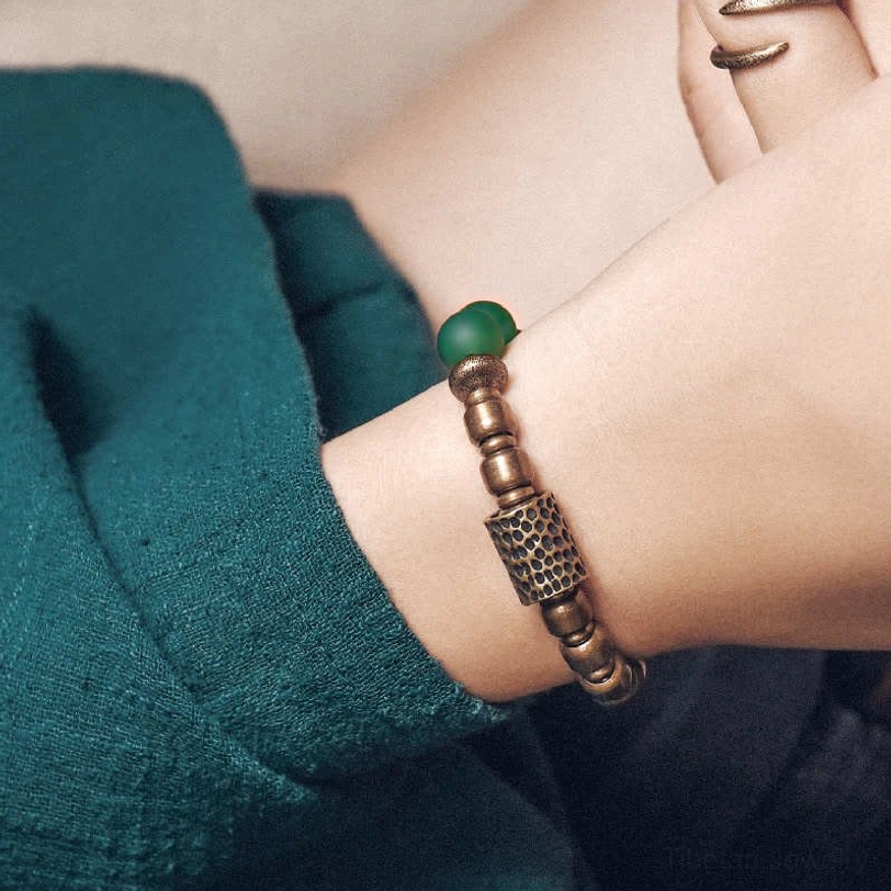 Green agate bracelet on wrist close-up showing single matte green bead with antiqued copper accents