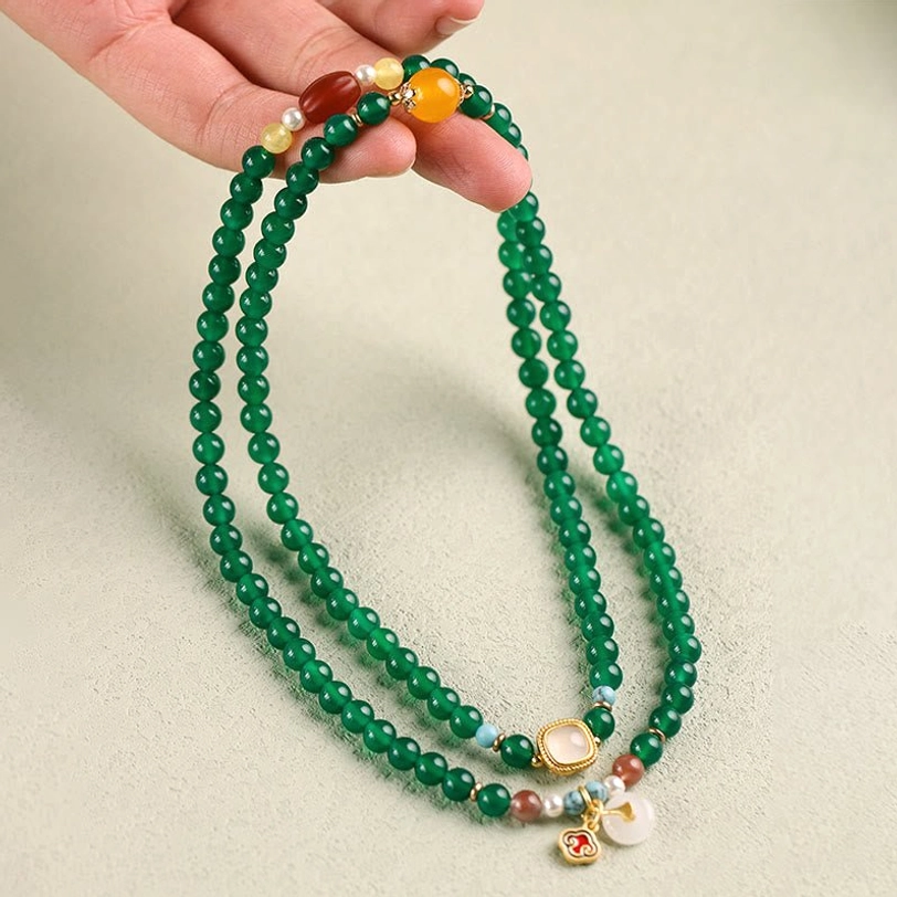 Hand holding Tibetan mala bracelet showing full length, beads, and peace buckle decorations