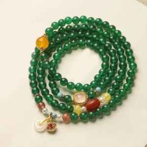 Green agate Tibetan mala bracelet with peace buckle charm displayed in flat lay overhead view