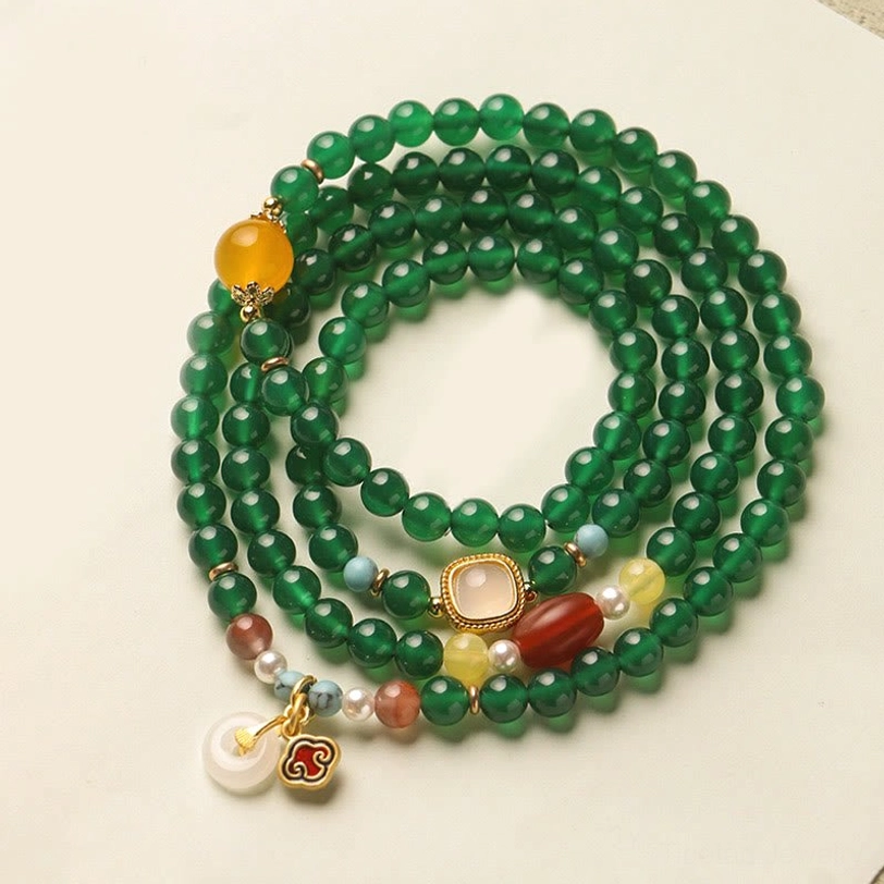 Green agate Tibetan mala bracelet with peace buckle charm displayed in flat lay overhead view