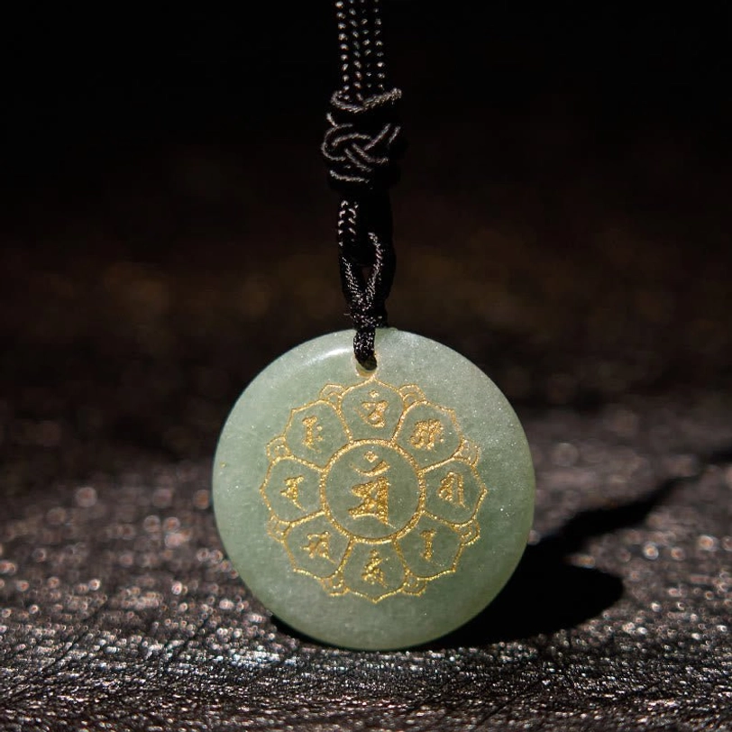 Green aventurine tibetan crystal pendant close-up showing mantra engraving and polished surface