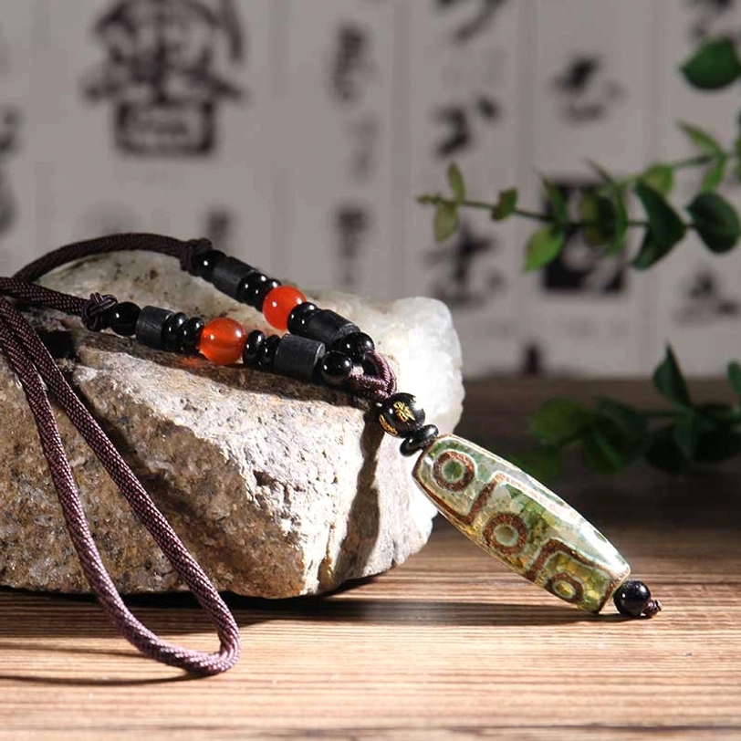 Green nine-eye dzi bead pendant necklace with brown rope cord and red agate beads lifestyle shot