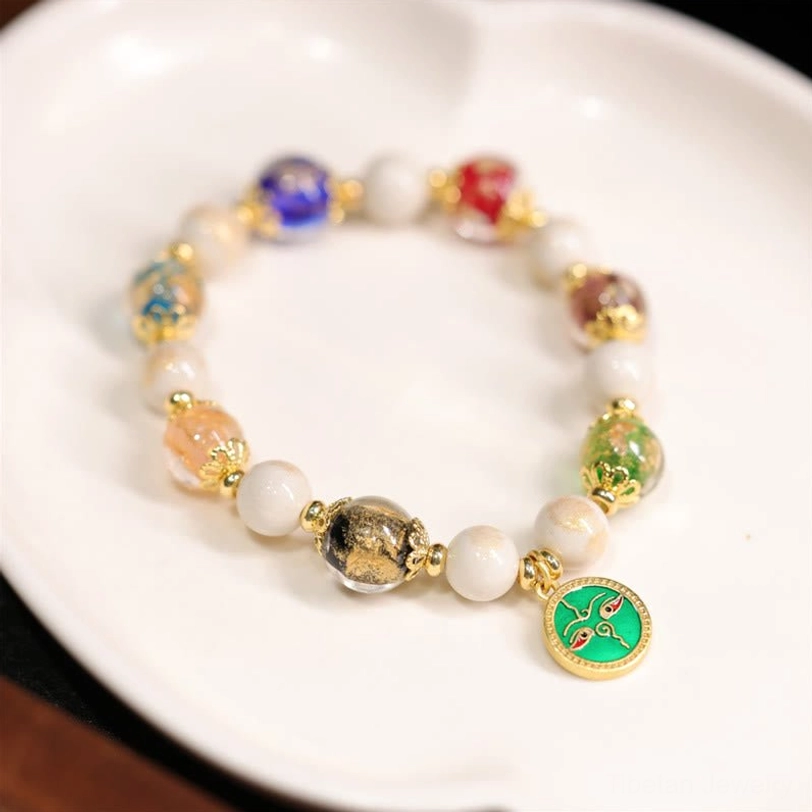 Green God of Wealth Tibetan blessing bracelet featuring green enamel facial charm, warm-toned mixed glass beads, and elastic string
