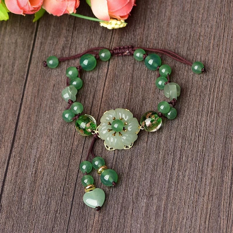Top-down view of adjustable green jade bracelet with braided cord and mixed green beaded chain on wooden texture
