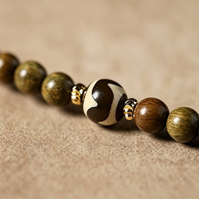 Green sandalwood mala bracelet with natural color variation and cat charm tassel on lifestyle display