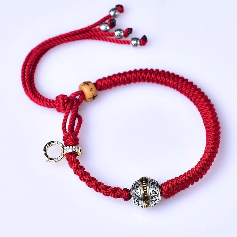 Flat lay overhead view of Green Tara red string bracelet showing adjustable crystal tassel ends, carved silver bead, and wooden accents
