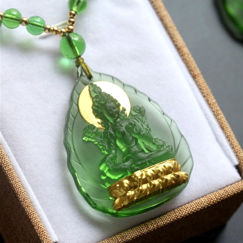 Teardrop-shaped Green Tara crystal pendant with gold Buddha base and halo, displayed in velvet jewelry box