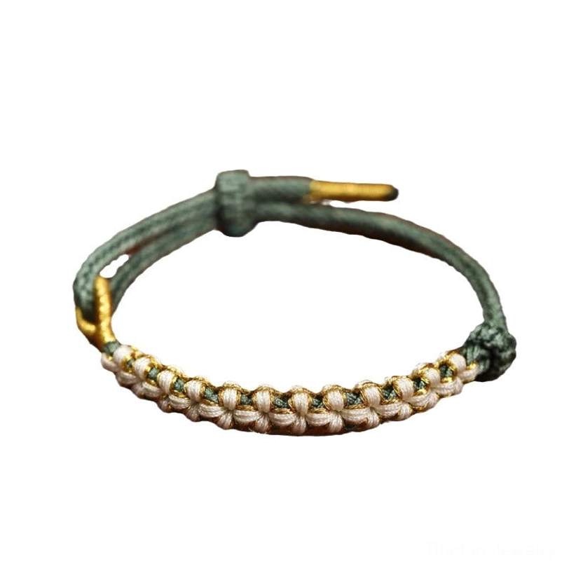 Green Tibetan peach blossom knot braided bracelet with gold metal details flat lay