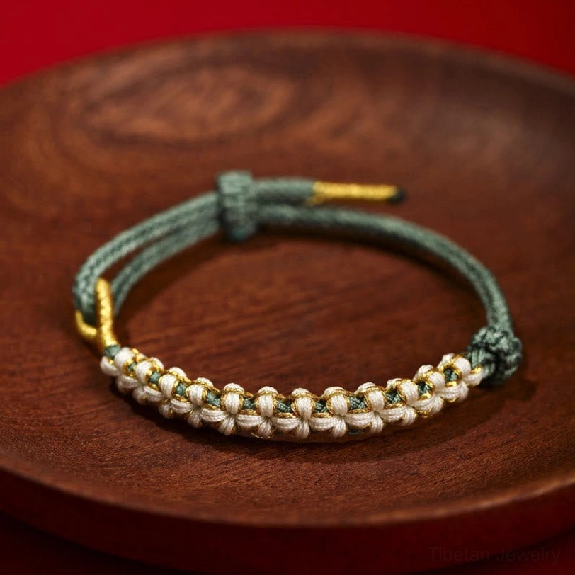 Dark green Tibetan braided bracelet with beige peach blossom knot and gold metal ends