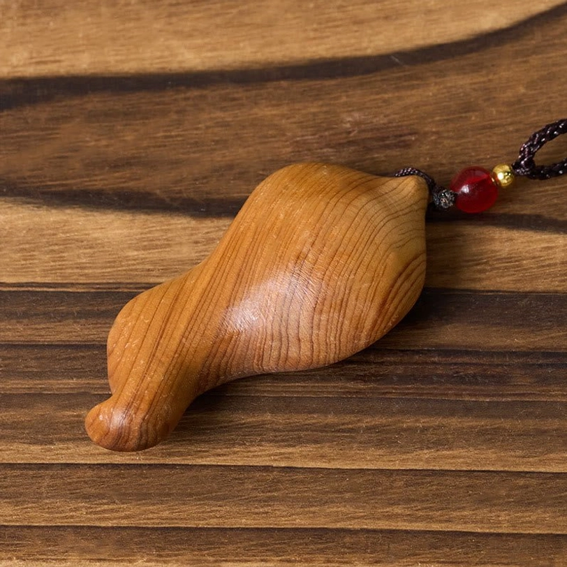 Guanyin pendant back view - smooth uncarved wood back with red bead attached to black braided cord