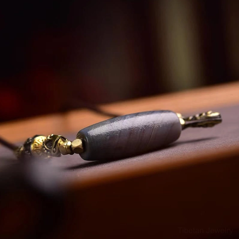 Single natural agate dzi bead with matte finish and brass end caps showing intricate banding pattern