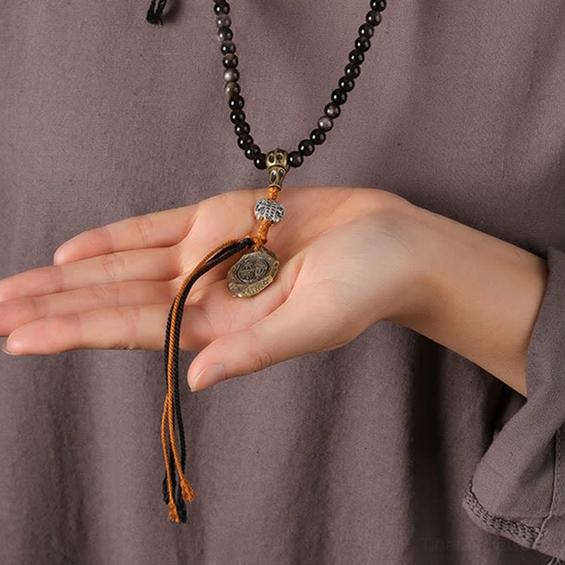 Hand-woven Tibetan Garuda obsidian necklace with braided tassel and copper alloy accents