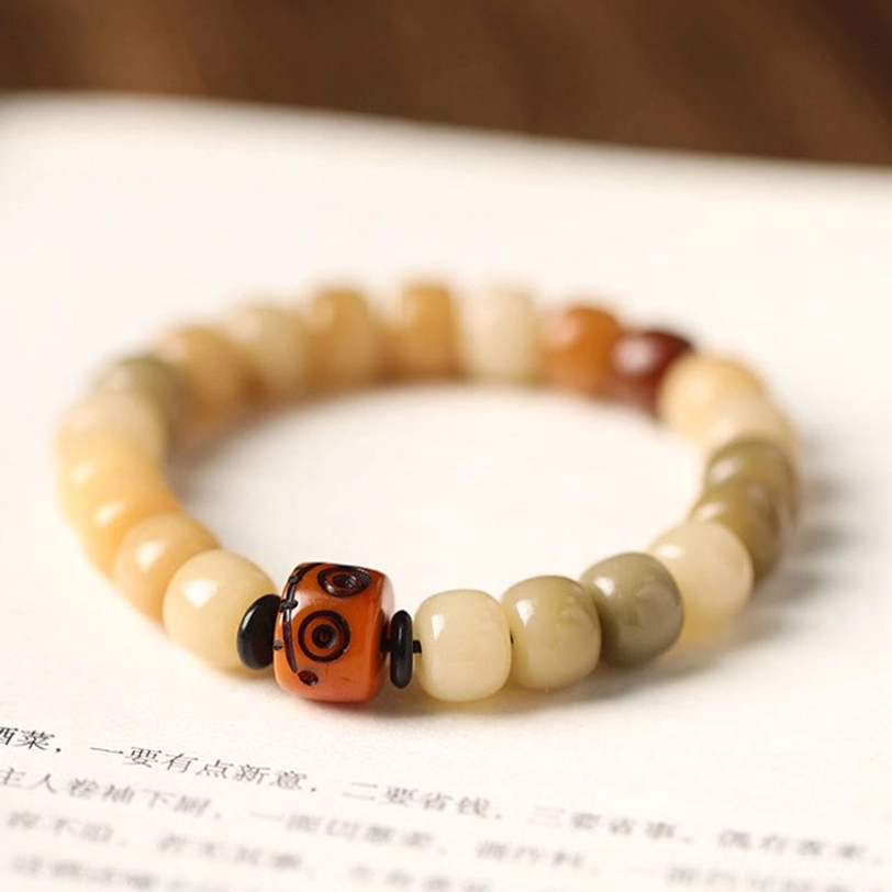 Handcrafted bodhi seed wisdom bracelet, product flat lay showing earth tone gradient beads with branded metal focal bead charm