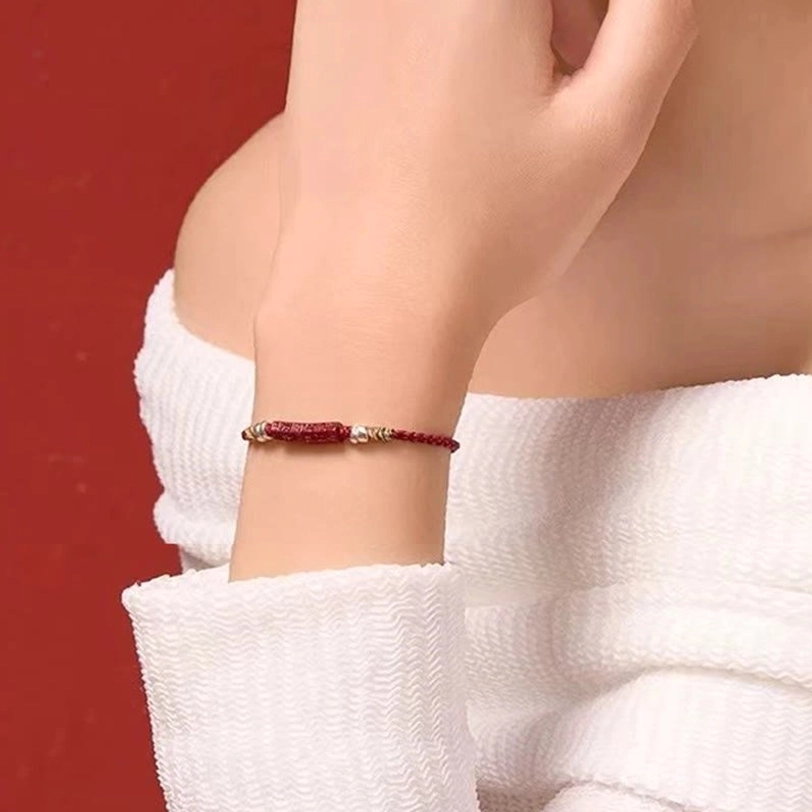 Handcrafted Tibetan red cord bracelet with carved cinnabar center and silver accents