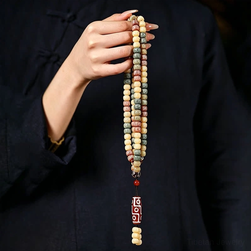 Handmade bodhi seed 108 bead mala with tibetan dzi bead pendant and tassel on neutral background meditation tool