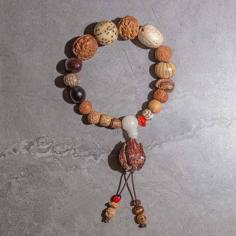Handcrafted Bodhi seed mala bracelet with earthy natural brown tones and lotus tassel, compact wearable meditation design