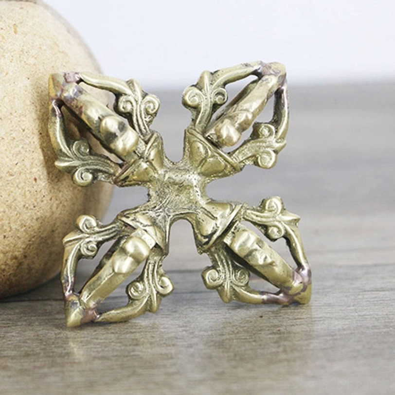 Handmade double dorje vajra from oblique side angle featuring antique brass finish, symmetrical cross design, and smooth polished metal texture