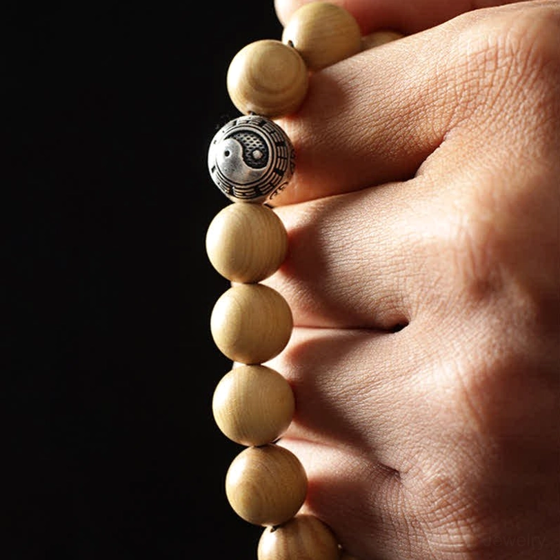 Handcrafted peach wood bracelet with single bagua silver spacer - held in hand close-up view