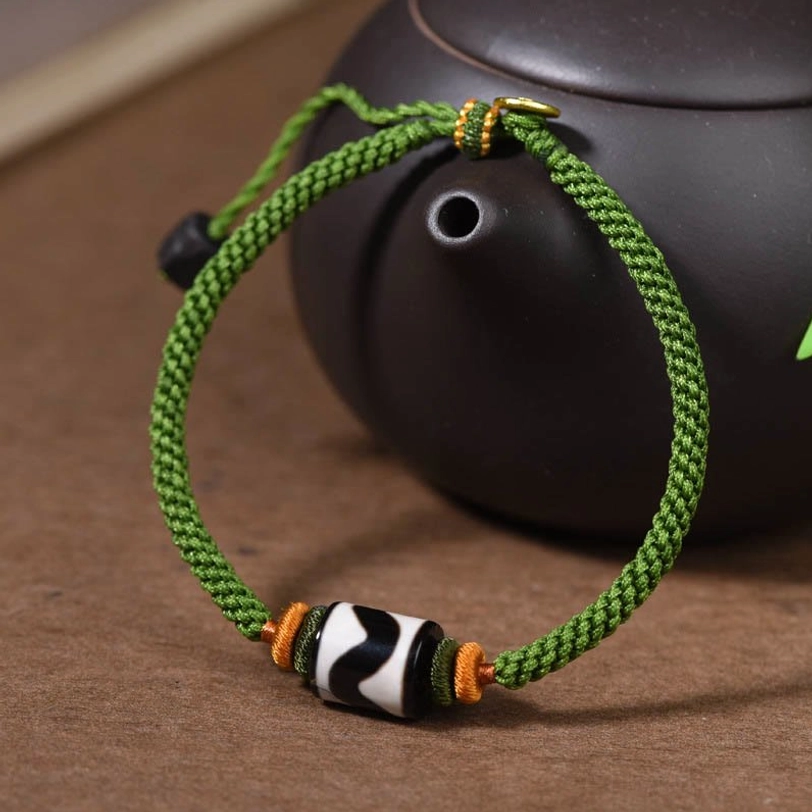 Handmade tibetan dzi bead green rope bracelet with natural material accents and protective amulet design