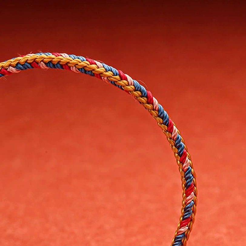 Tibetan blessed string bracelet flat lay displaying tightly woven red blue and gold cord