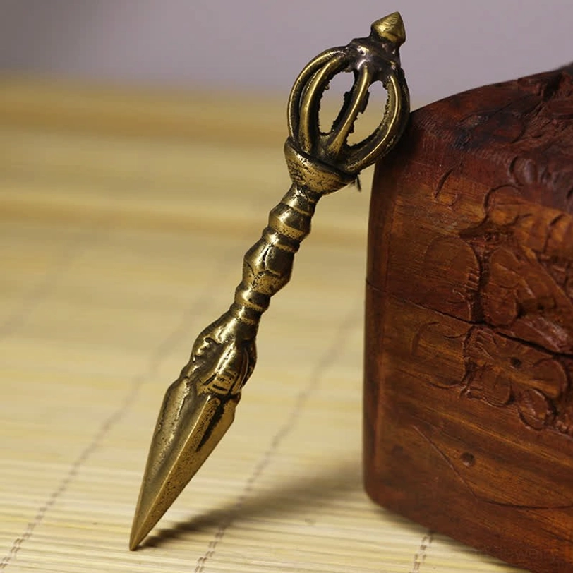 Authentic Nepalese handmade copper vajra dagger with detailed carved handle and pointed ceremonial spear tip displayed on bamboo mat