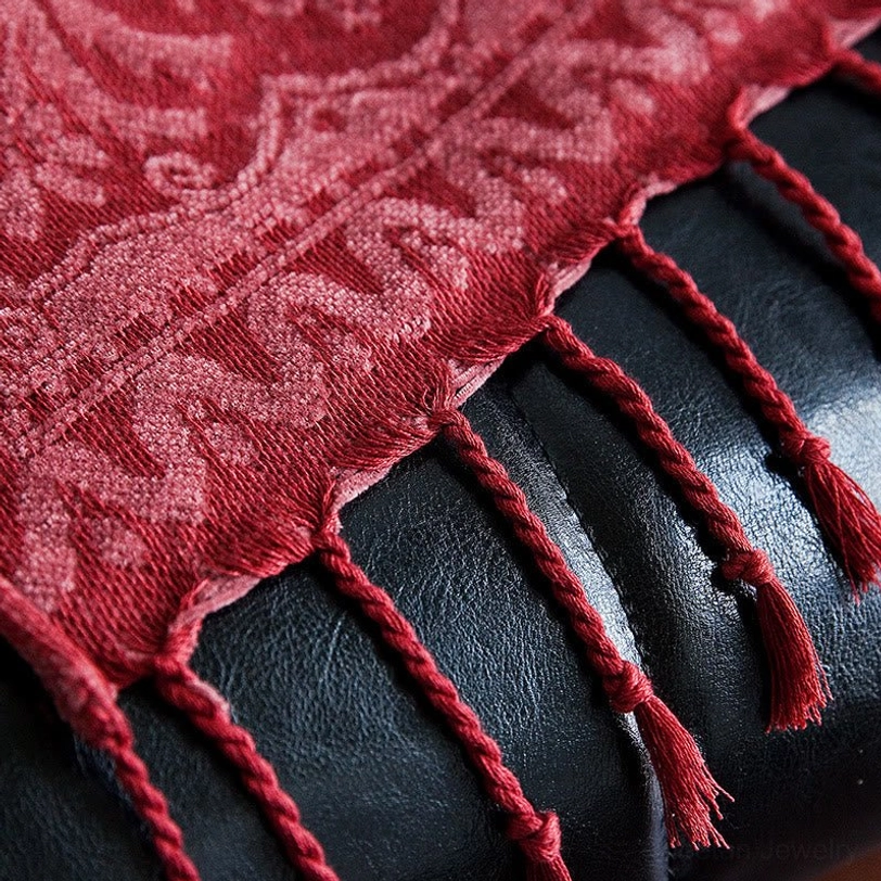 Ultra close-up macro view of handwoven Tibetan blanket texture, showcasing braided tassels and damask woven pattern in chenille fabric