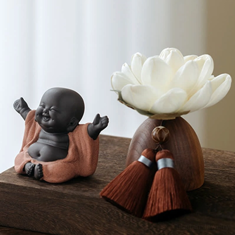 Happy sitting Buddha figurine with bare chest in terracotta robe and lotus holder display