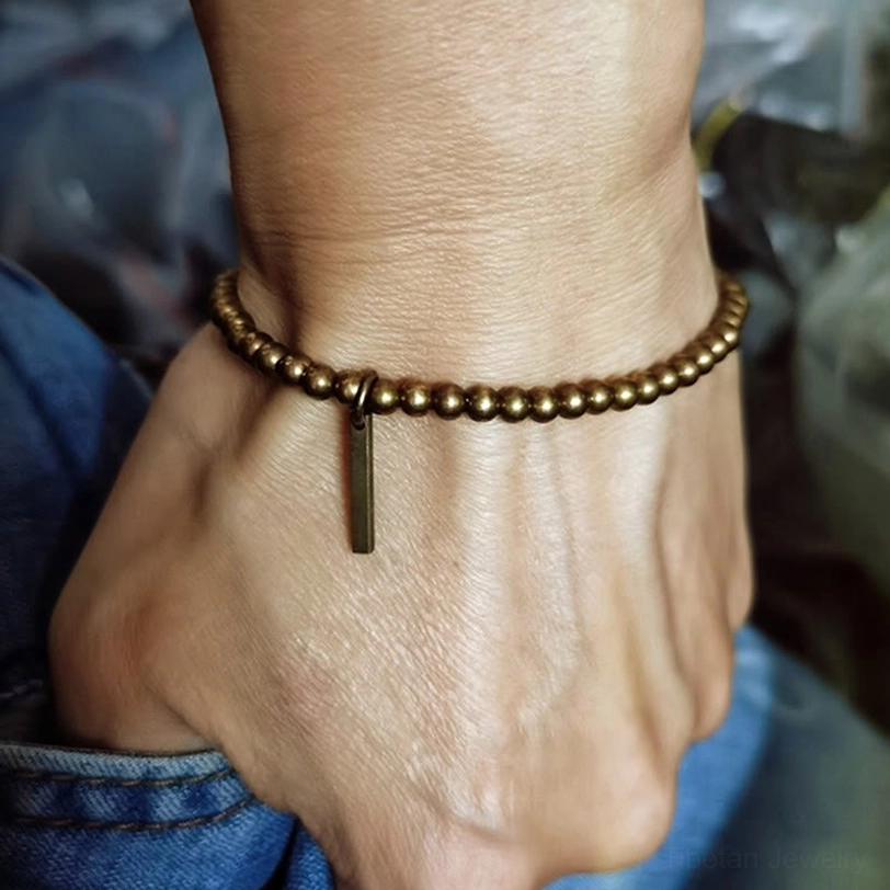 Minimalist copper brass bracelet on wrist with long bar pendant decoration detail