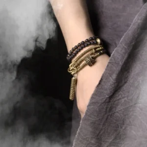Vintage black lava stone and antique brass stacked bracelets worn on wrist with tassel pendant