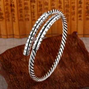 Heart Sutra copper twisted bangles - three-quarter side view displaying antique silver finish, spiral twisted band, and engraved sutra on bamboo backdrop