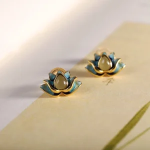 Hetian cyan jade lotus stud earrings pair with gold plating displayed on vintage stationery background, showing delicate lotus flower design