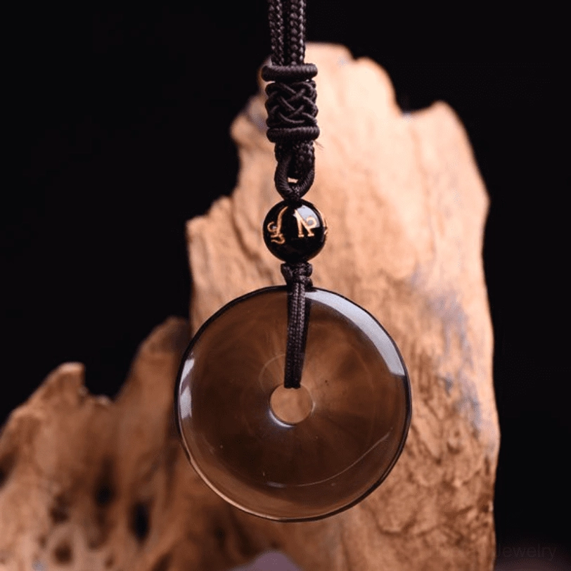 Ice obsidian necklace side view showing smooth translucent surface and hand-braided brown cord