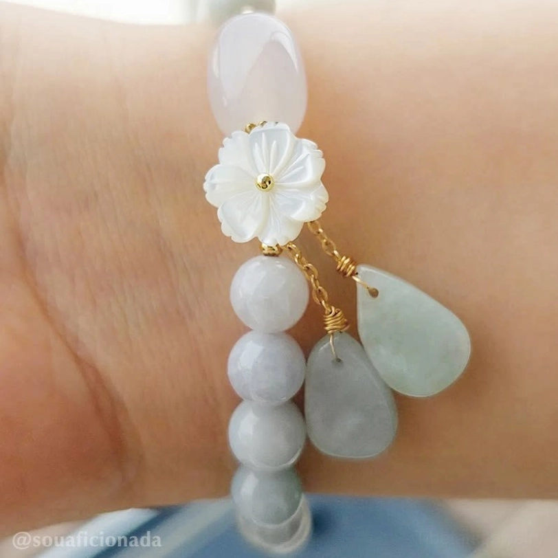 Jade bracelet with stacked teardrop beads and shell flower pendant shown side close-up on wrist