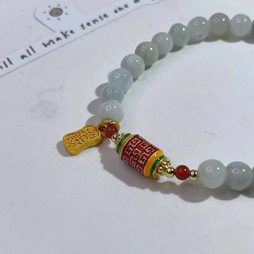Close-up side view of jade prayer bracelet charm assembly and bead strand detail