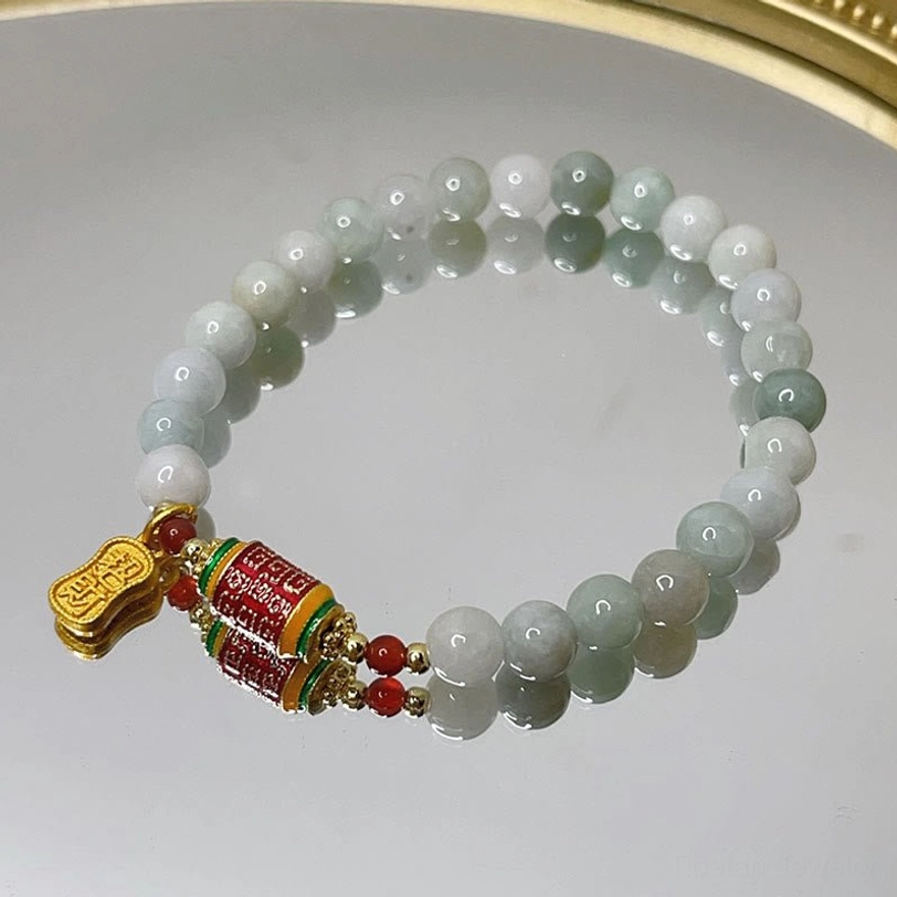 Tibetan jade fu prayer wheel bracelet full overhead view on decorative gold-rimmed mirror tray