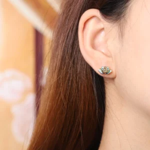 Single cyan jade lotus stud earring worn on earlobe, close-up detail showcasing jade stone and silver backing in natural light