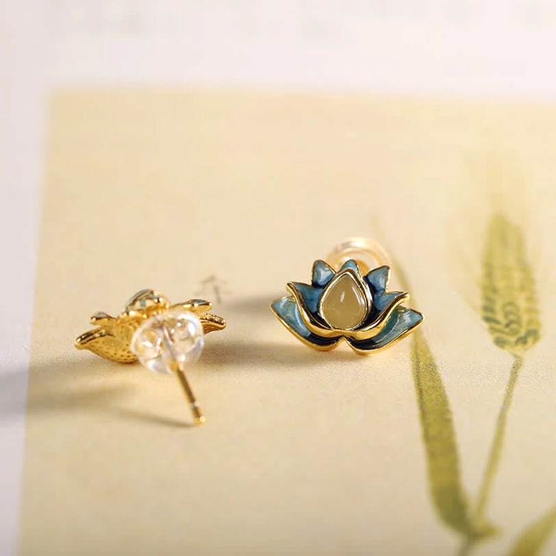 Hetian jade lotus earrings pair displayed at oblique angle on vintage wheat print paper, showing both sides of handmade design