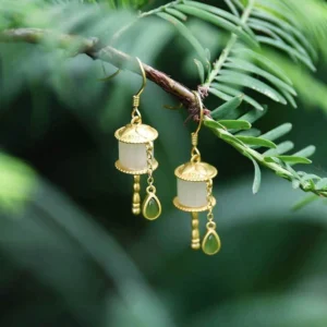 925 sterling silver jade prayer wheel drop earrings with green teardrop jade stone pendant, outdoor natural lighting on conifer branch