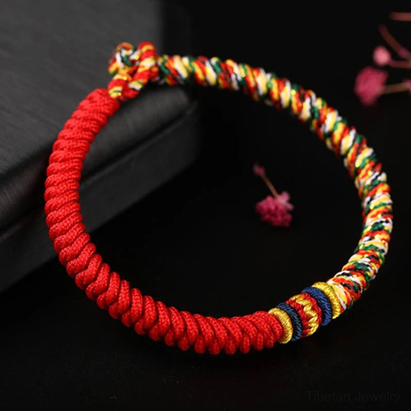 Full circle Tibetan King Kong Knot bracelet with red base and colorful woven ends overhead view