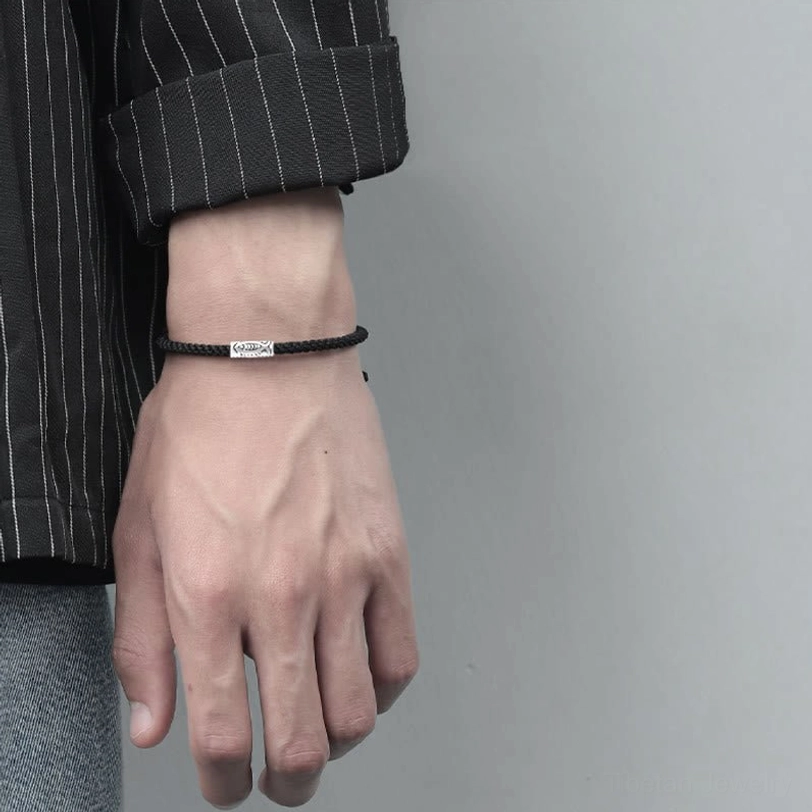 Engraved silver fish charm black woven rope bracelet on pinstripe shirt displaying slim fit