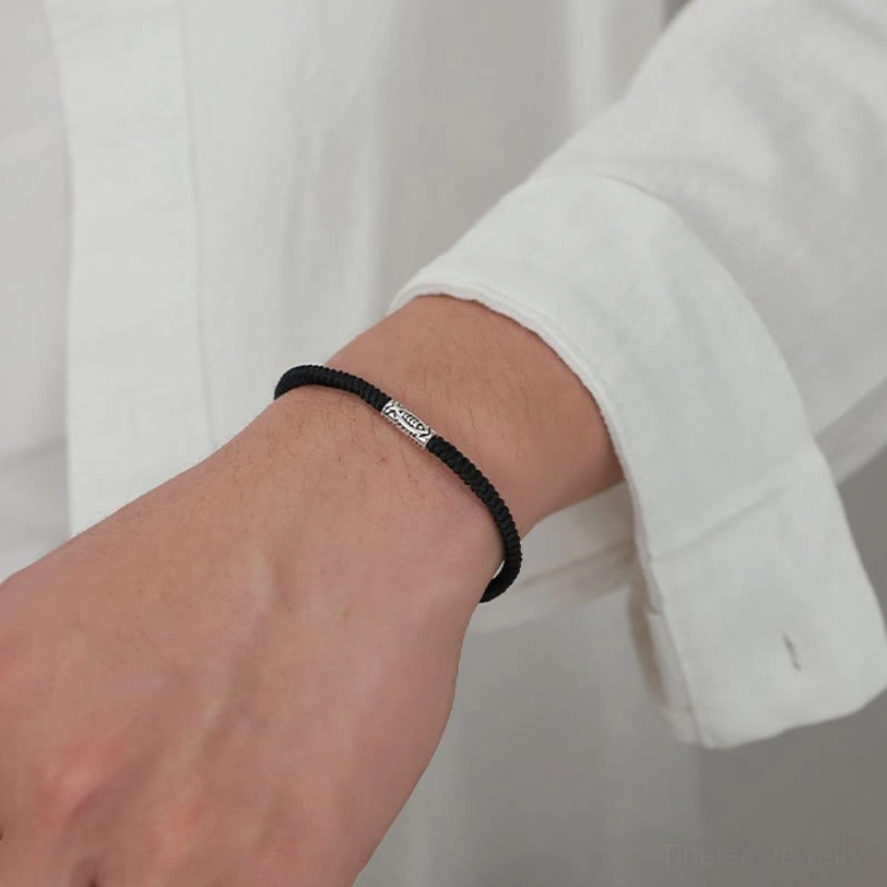 Slim koi fish charm bracelet worn on wrist with white shirt cuff showing minimalist design