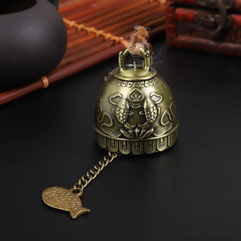 Double koi fish embossed Tibetan wind chime bell with twin fish carvings and bronze metal texture on vintage background