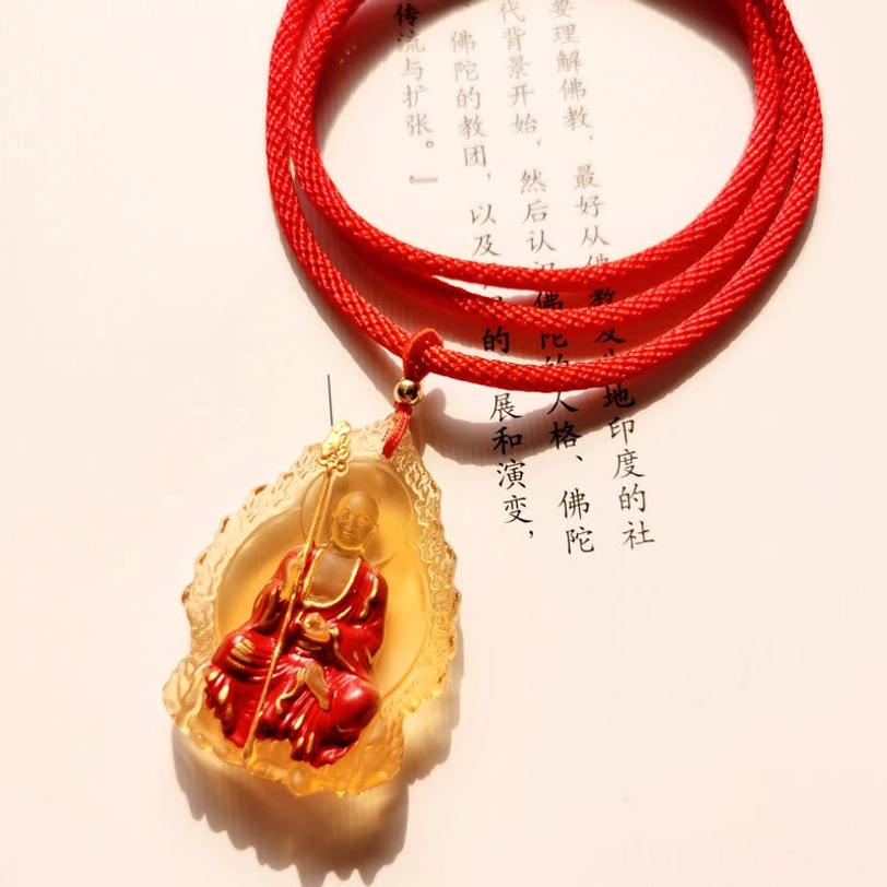 Amber gold Ksitigarbha Buddha Liuli crystal pendant with flame border, seated bodhisattva motif, and red braided cord chain