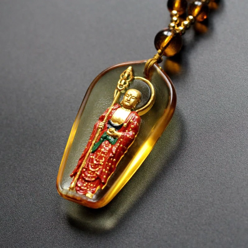 Amber Ksitigarbha Buddha Liuli crystal necklace with standing bodhisattva pendant and brown beaded chain, close-up oblique view