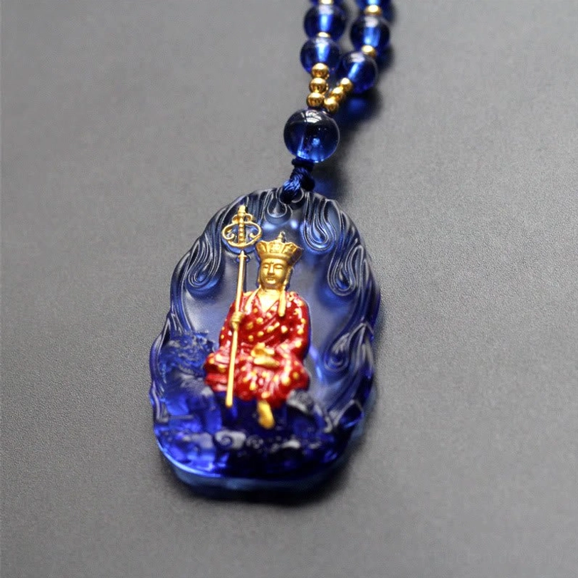 Sapphire blue Ksitigarbha Buddha Liuli crystal pendant with flame edge, seated gilded bodhisattva, and blue beaded necklace