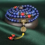 Lapis lazuli tibetan mala bracelet 108 beads top view on wooden display with red turquoise accents